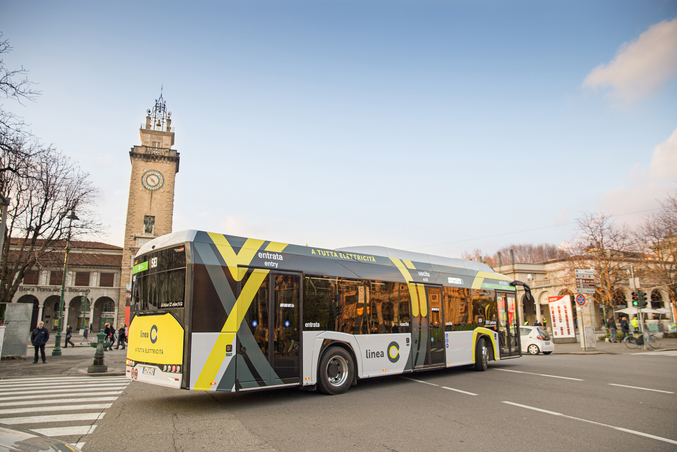 Bérgamo desde arriba, con muchos tejados de casas y una calle arbolada muy concurrida.