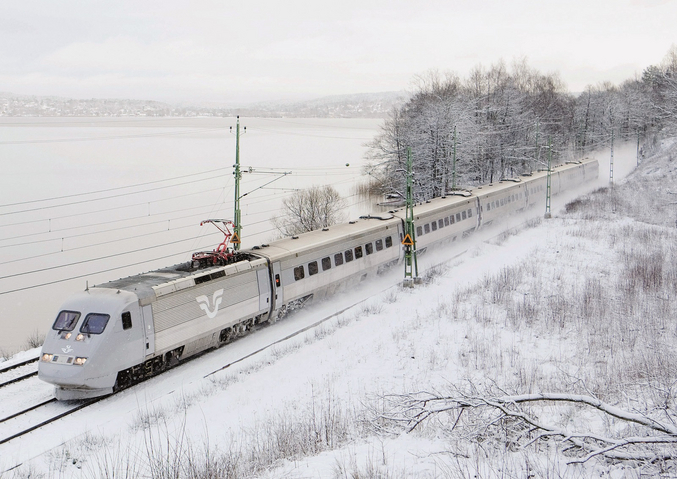 Un tren blanco de SJ en la nieve frente a un lago helado.
