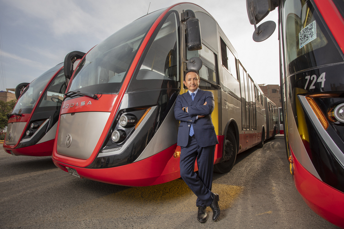 Polo Peréz, director general del Grupo Polo, se apoya en un autobús rojo del Grupo Polo aparcado junto a otros dos autobuses rojos en una cochera.