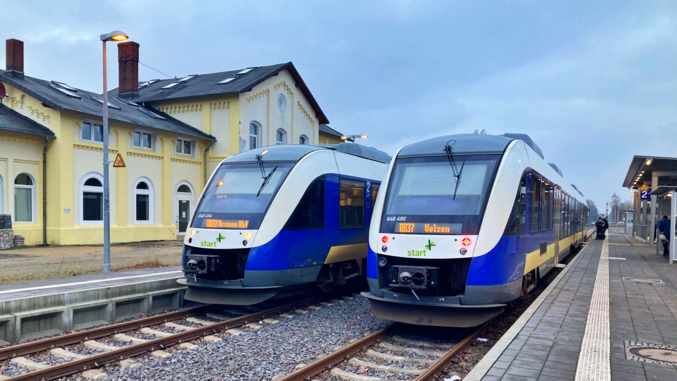 Dos trenes azules y blancos de salida se paran en una estación.